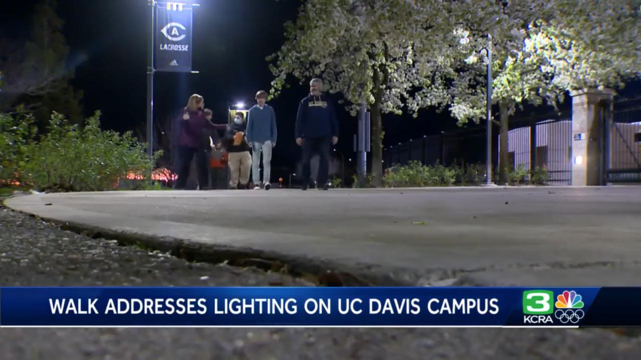 Group walks along path, under overhead lamp, to check on lighting safety