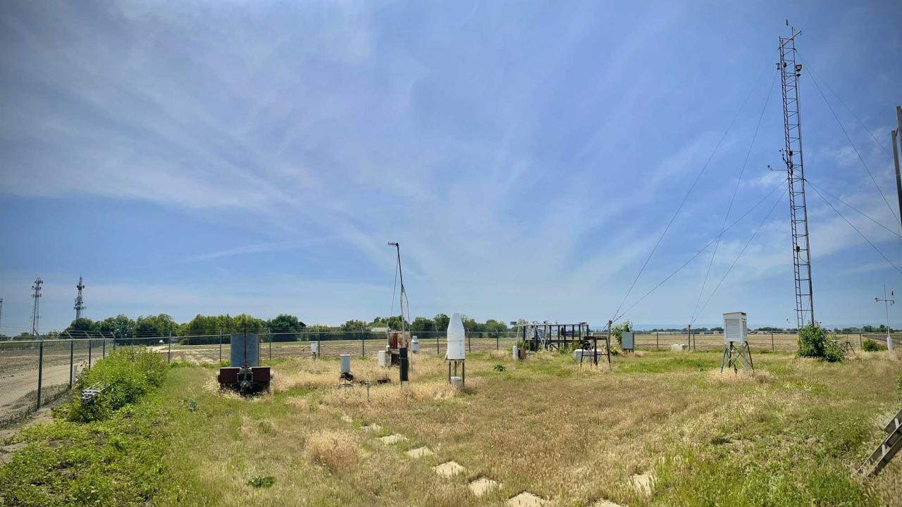 Blue sky in background of campus weather station with post, dials, and other equipment.