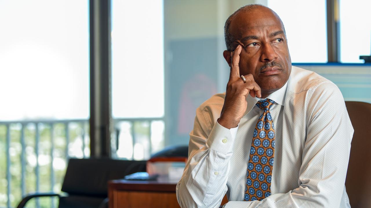 Chancellor Gary S. May sits at desk.