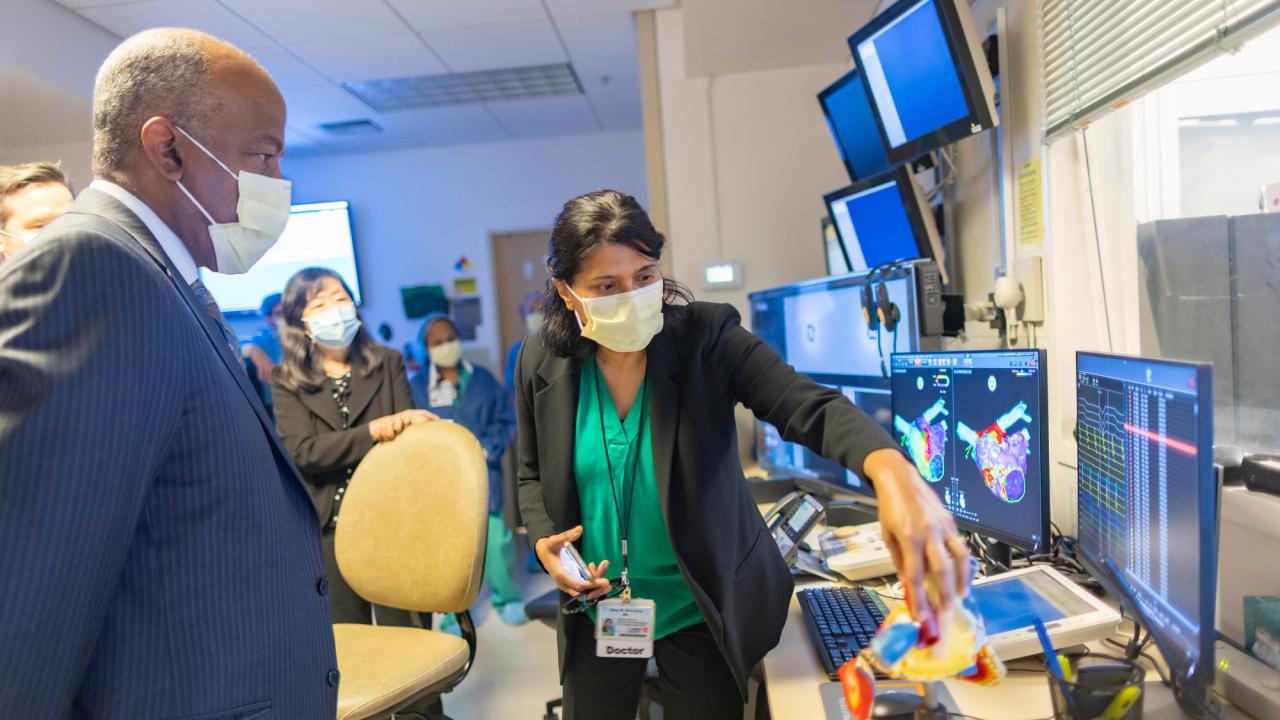 Chancellor Gary S. May, in face mask, observes as Uma N. Srivatsa shows a model of the heart
