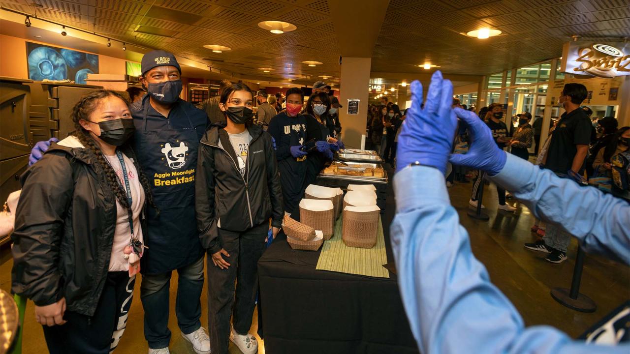 Chancellor Gary S. May poses for photo with students at Moonlight Breakfast