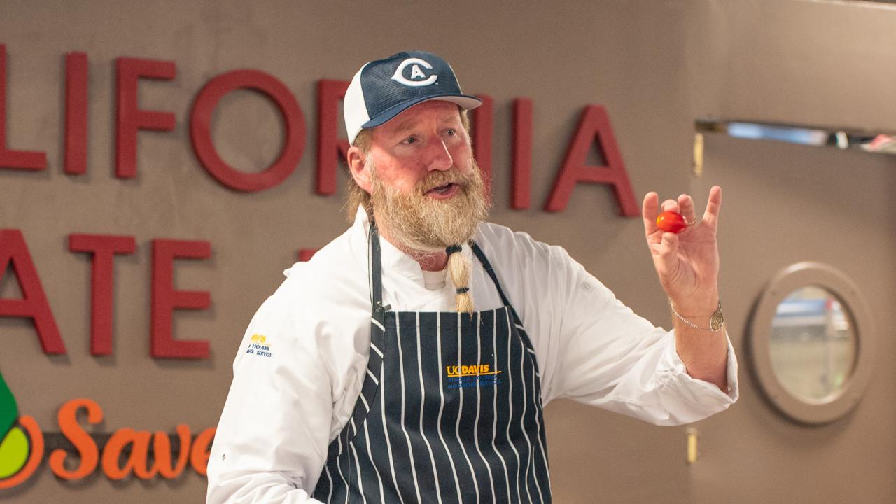 Chef displays a Roma tomato during cooking demonstration