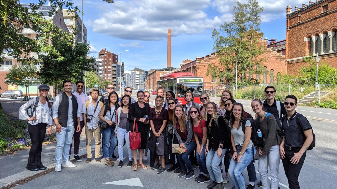 A group poses in front of a brick building. 