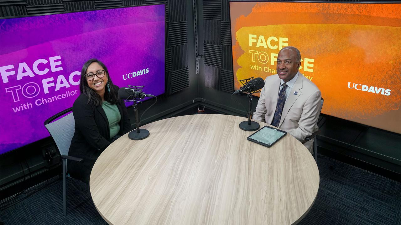 Deniss Martinez and Chancellor Gary S. May pose for a photo in a recording studio.