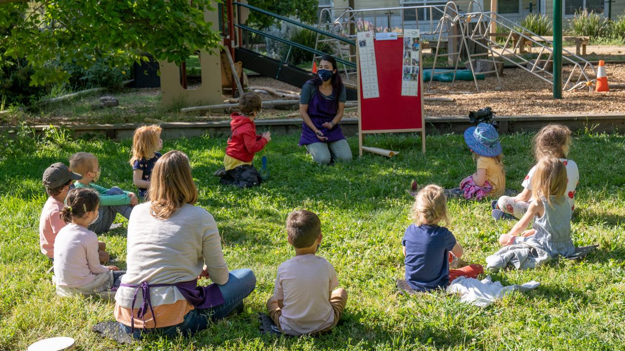 Children sit in circle for class held outdoors.