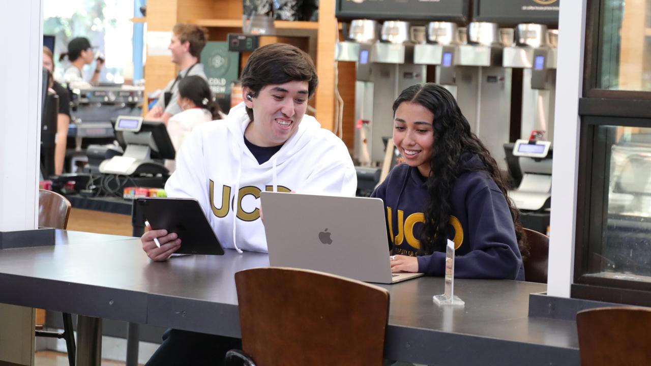 Two students look at the screen of a laptop in the Coffee House.