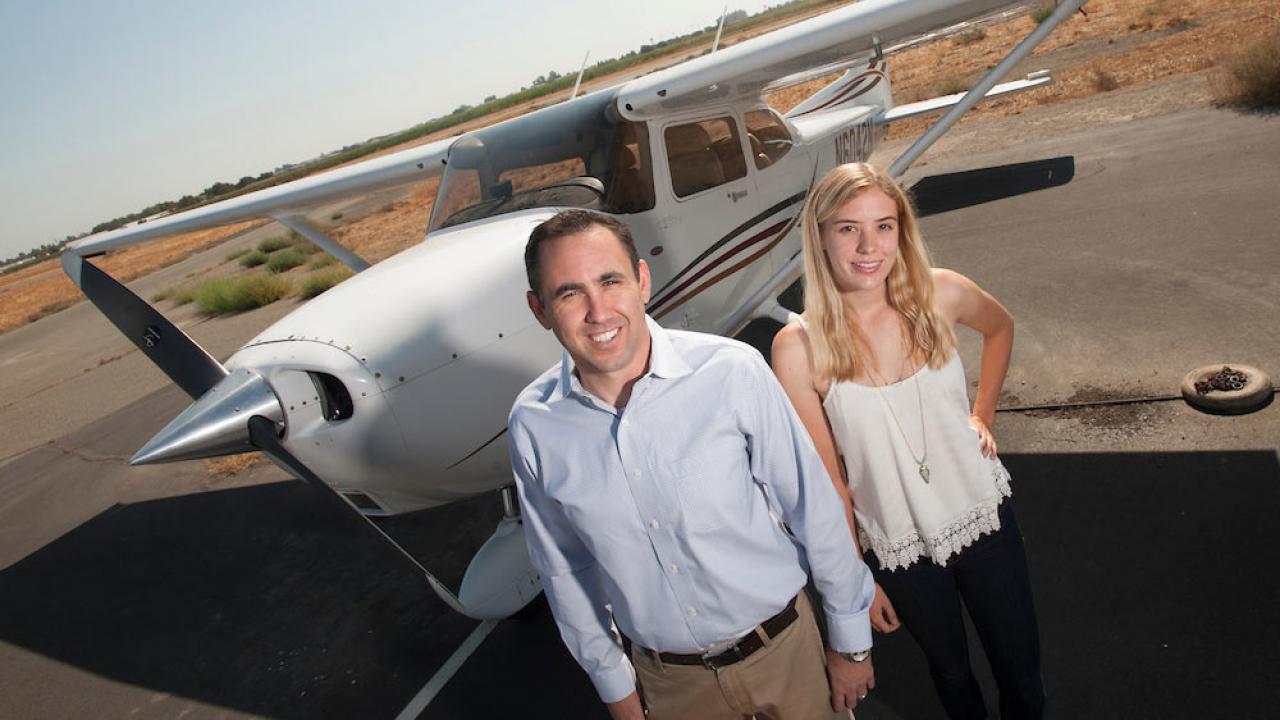 An instructor and student pose for a shot in front of an airplane at UC Davis airport