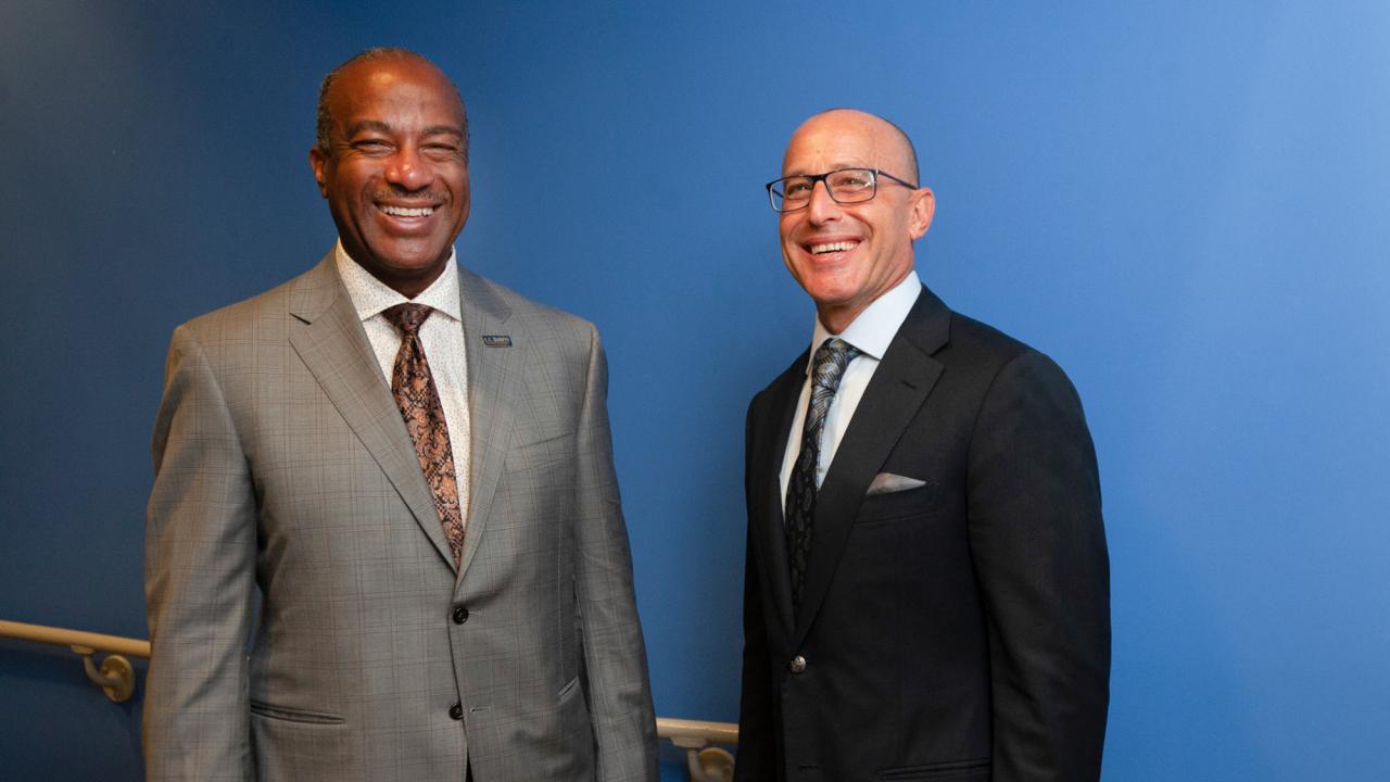 Gary S. May and David Lubarsky, both in suit and tie, pose side by side, smiling.