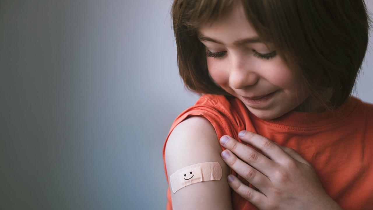 Girl stares at her vaccination Bandaid.