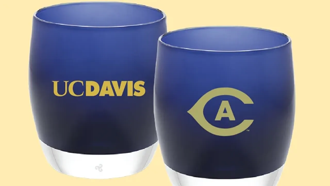 Two blue frosted candleholders with yellow UC Davis text and circular CA logo