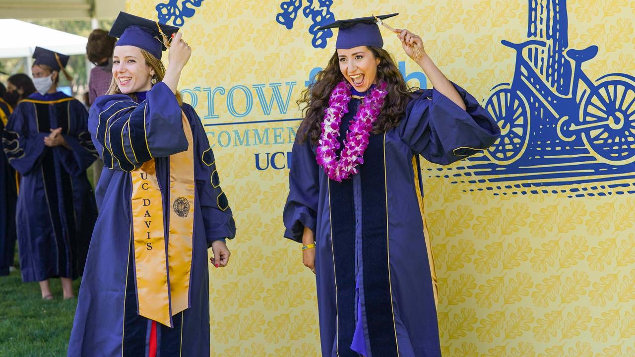 Graduate students wearing graduation regalia move their tassles. 