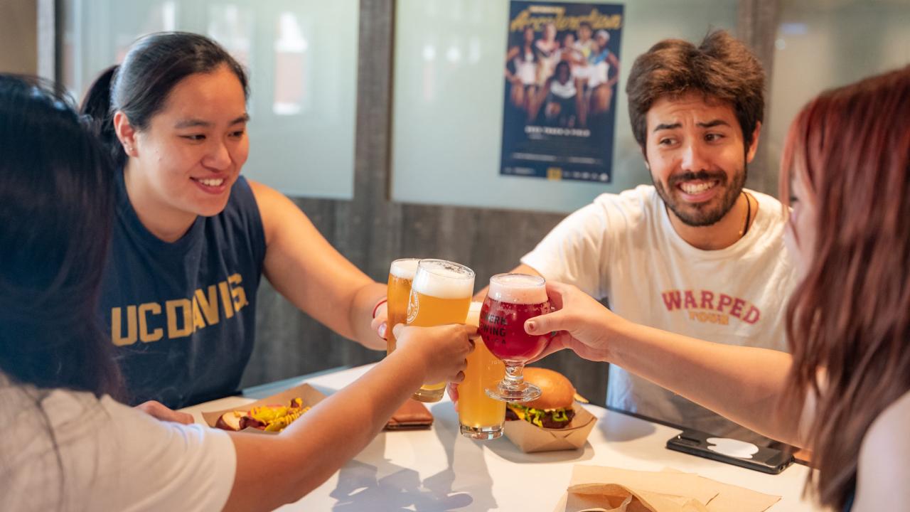 Four people clink their glasses together at restaurant table