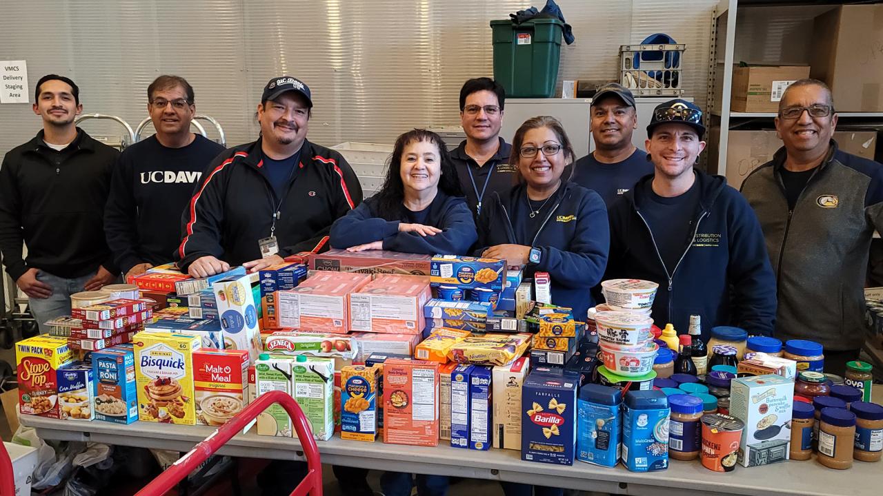 Mail Services personnel pose behind a tableful of donated food