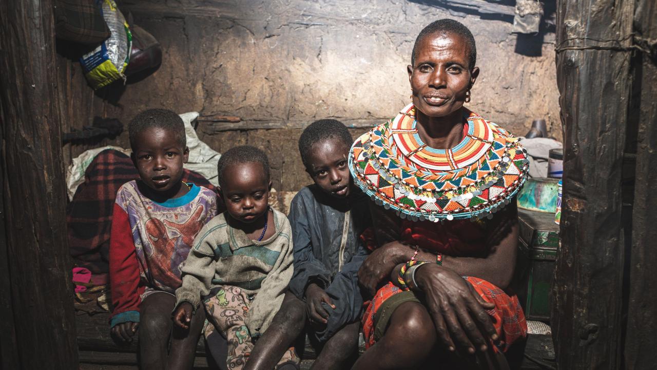 Three young children sit next to their mother in their home in Samburu, Kenya.