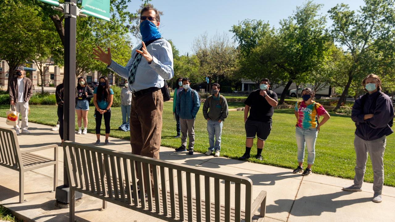 Teacher and students in face coverings, on walking tour, outdoors.