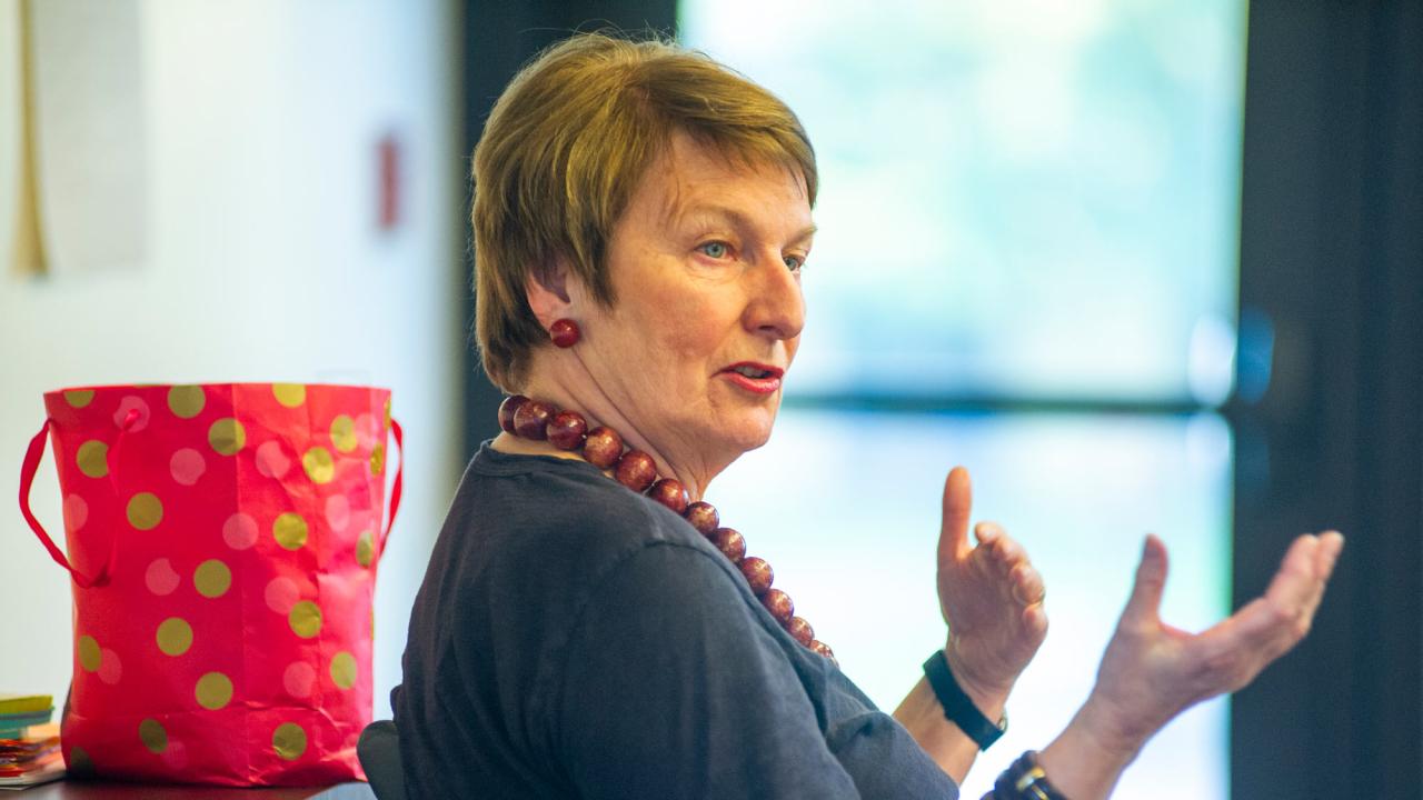 Joanna Regulska, hands outstretched in front of her, leads a seminar.
