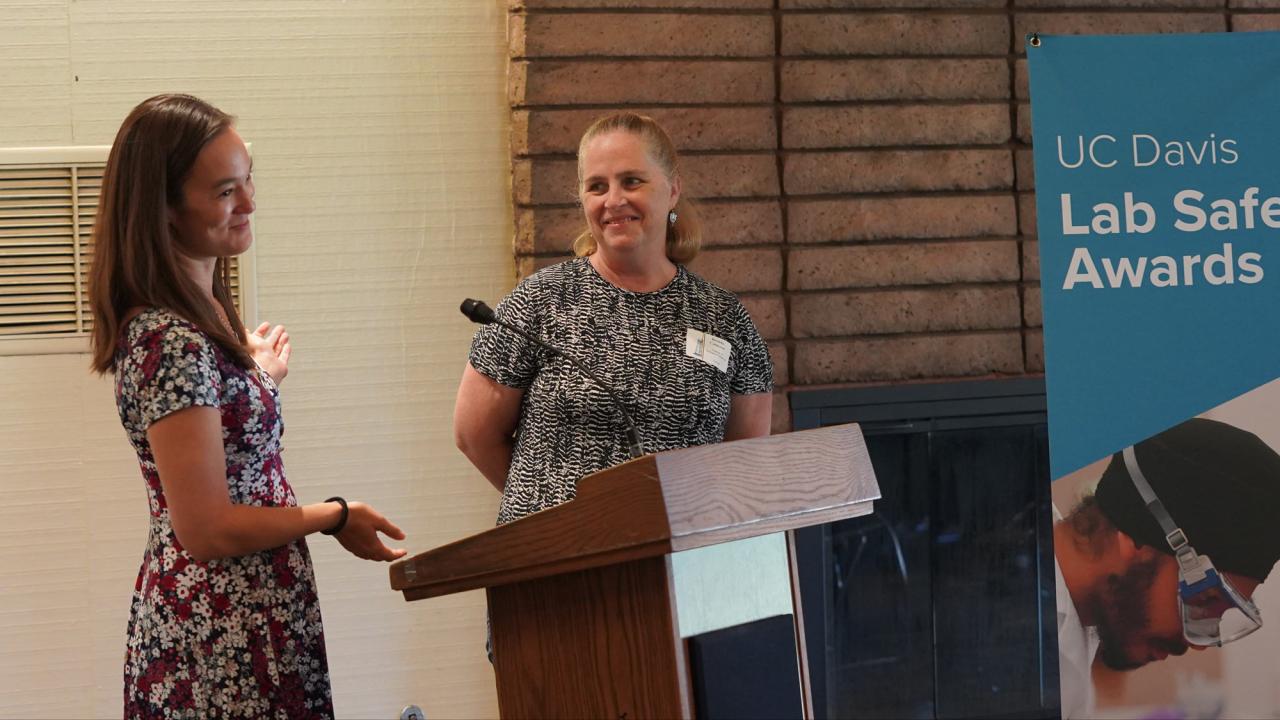 2 award winners stand at podium at UC Davis