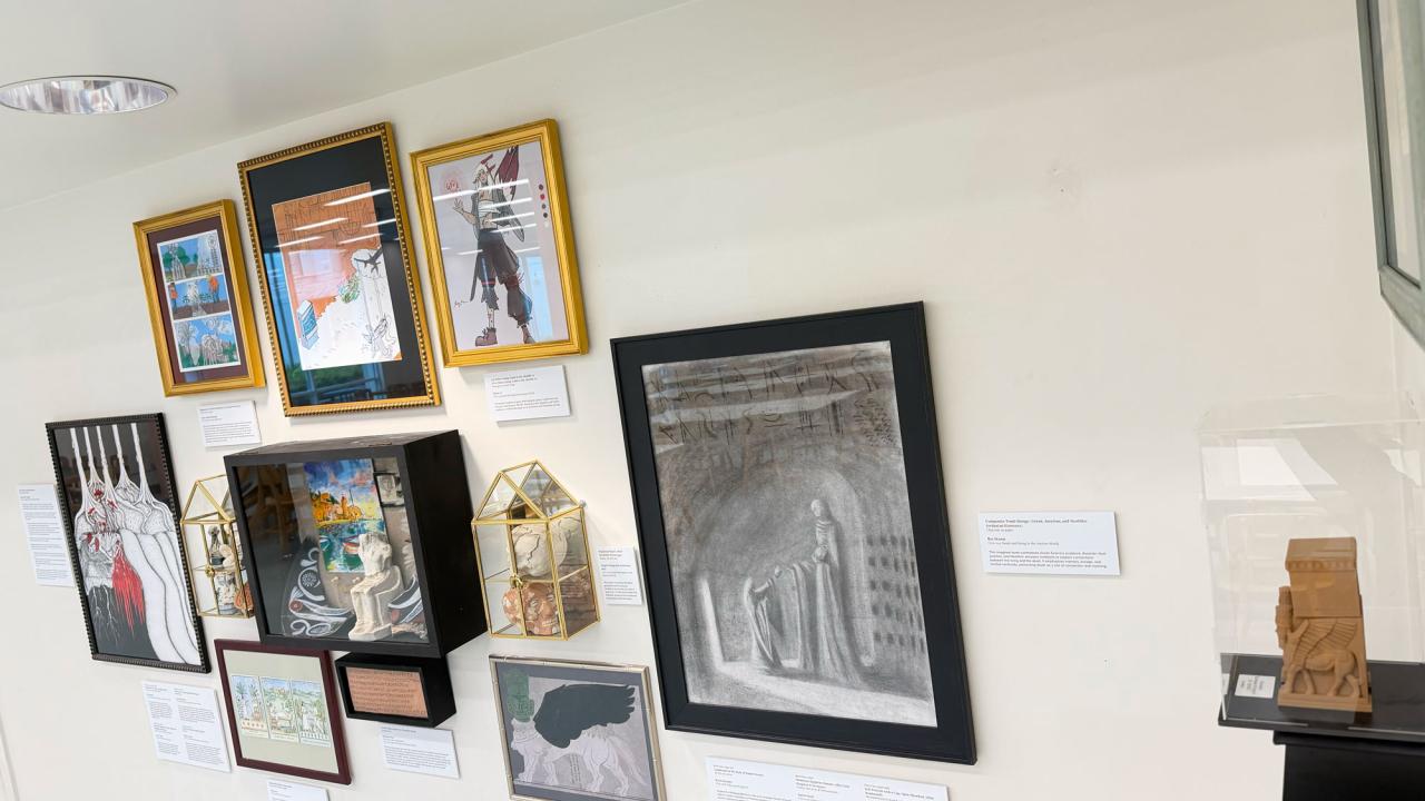 Gallery wall with assorted framed artworks and small sculptures on a shelf.