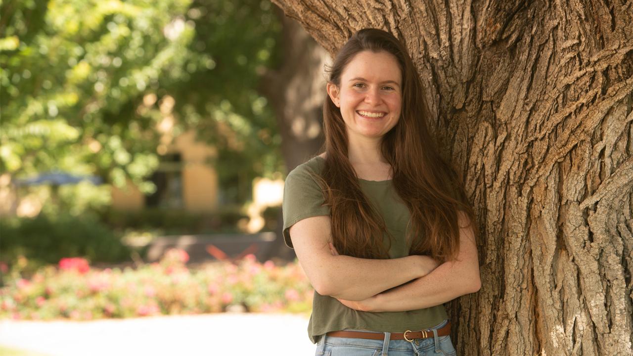 Madeline Bright leans against a tree