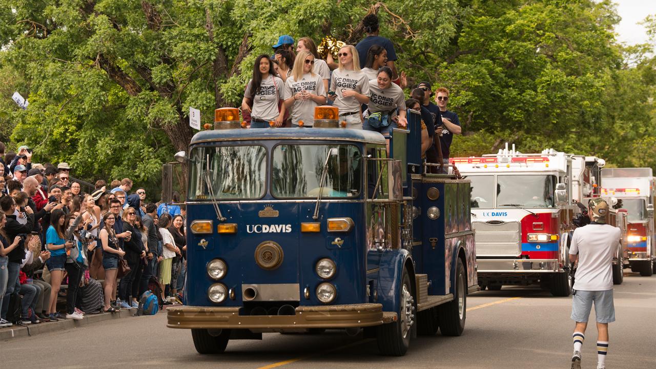 Basketball teams ride on top of antique fire engine in Picnic Day parade.