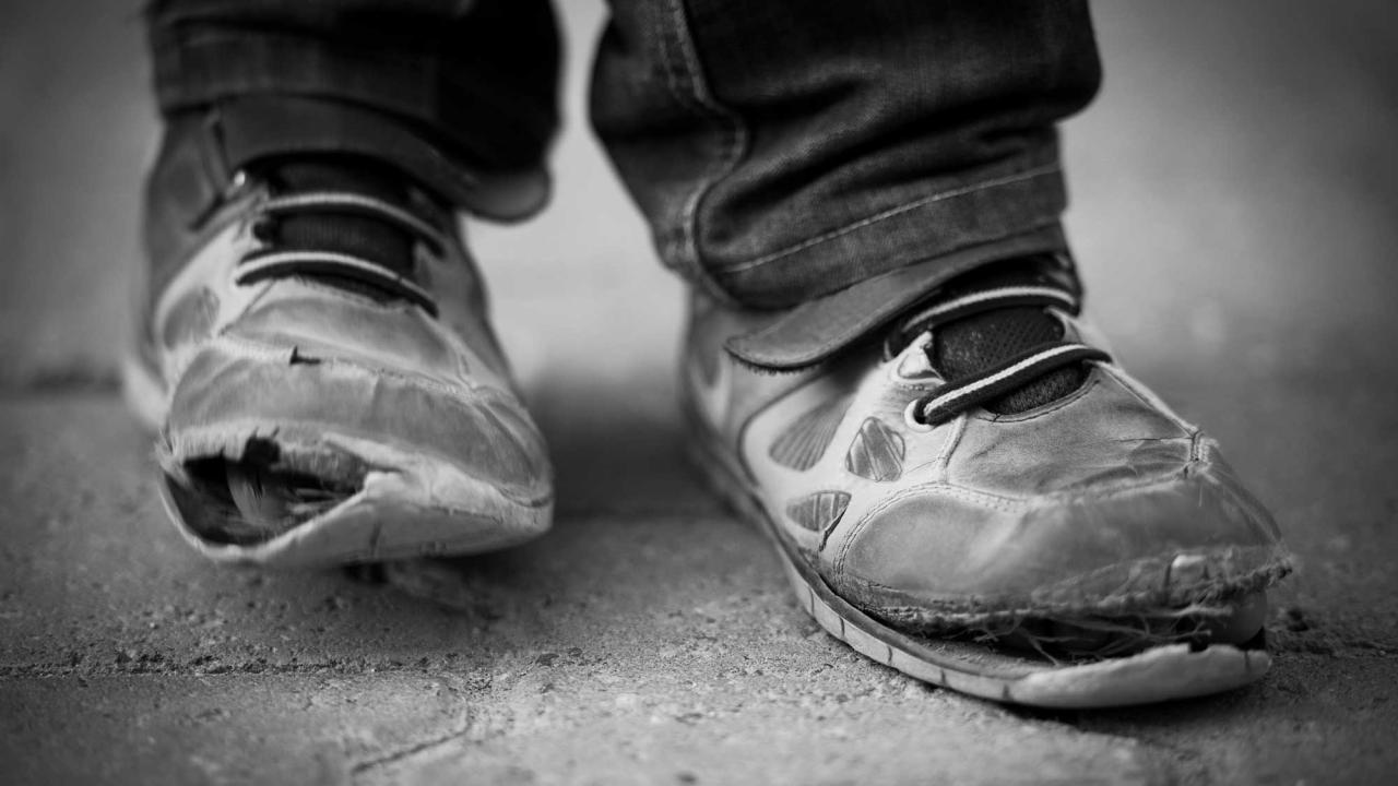 Worn out tennis shoes on feet.