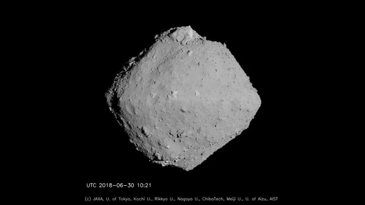 A grey, diamond-shaped object with pitted, cratered surface against a black background. 