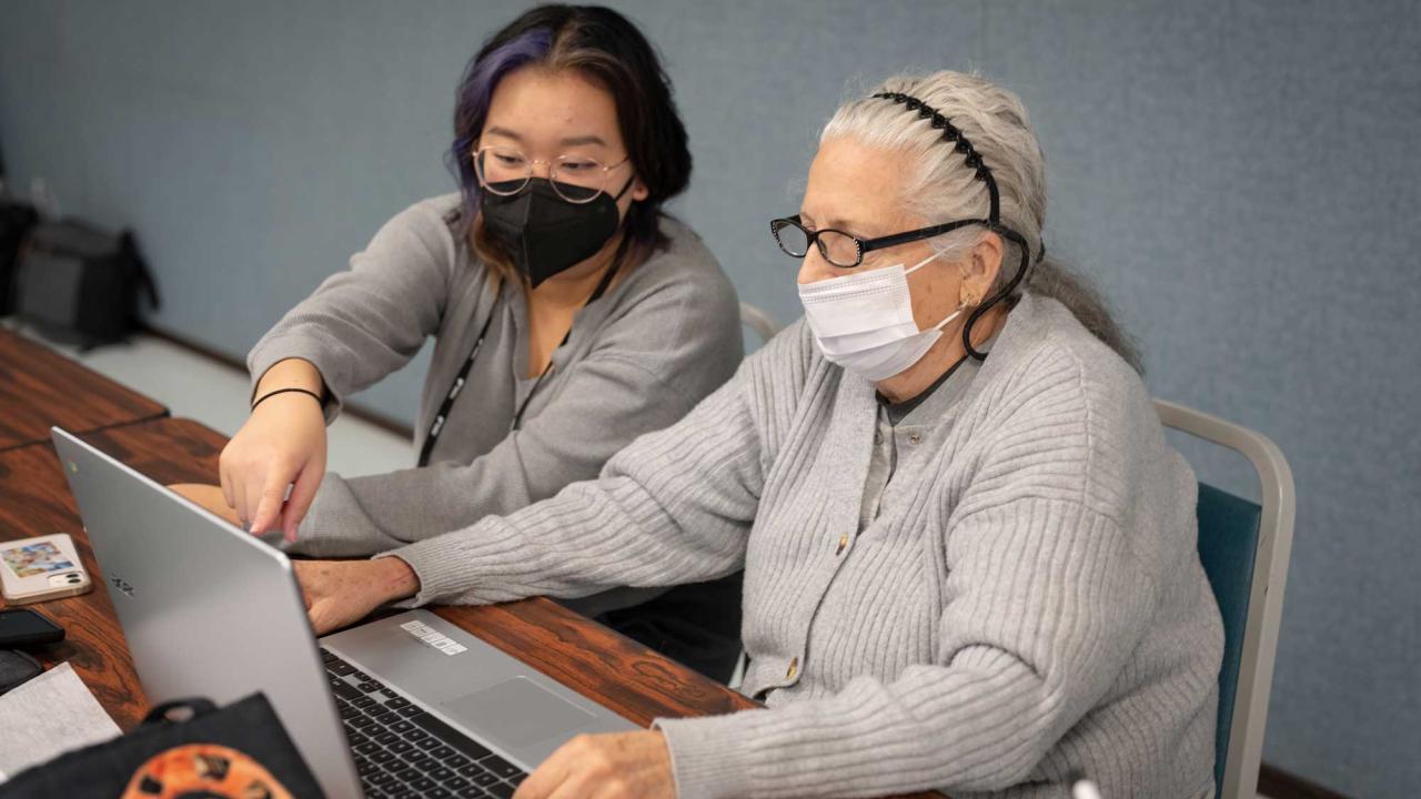 woman with brown hair aids older woman in UC Davis class