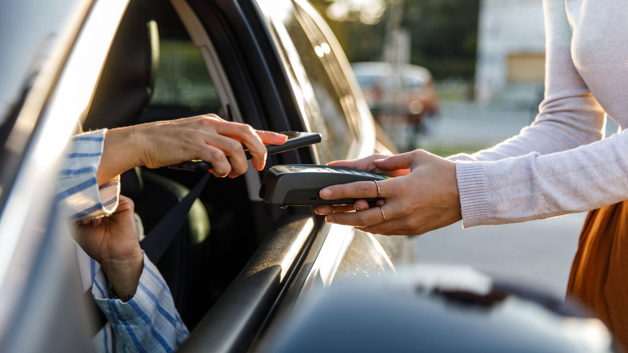 Hands of people doing a phone purchasing transaction from a car