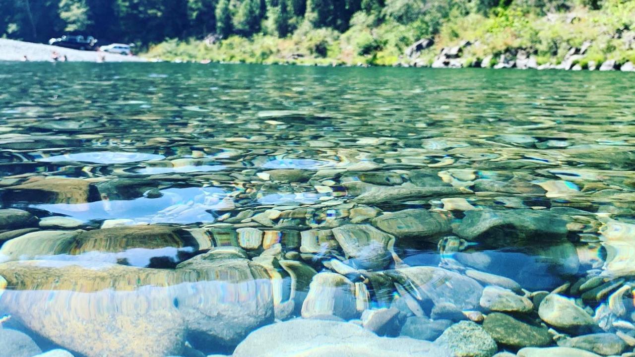 eye level view of clear water and stones of Smith River in summertime