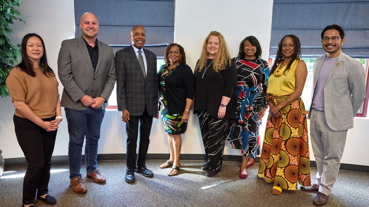 8 people standing, posed, award recipients, speakers and a presenter at Soaring to New Heights, 2023 and 