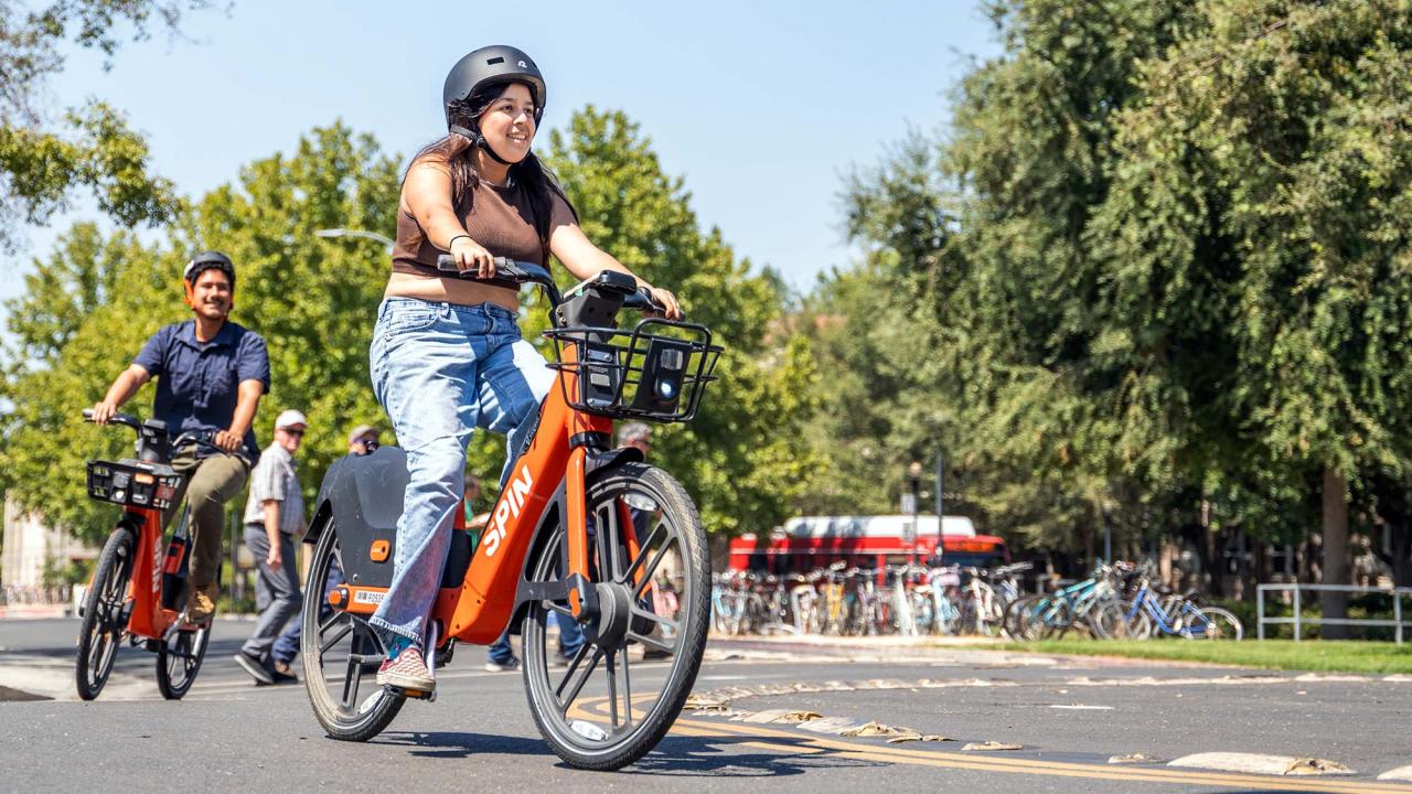 Two students ride Spin Bikes through bike circle 