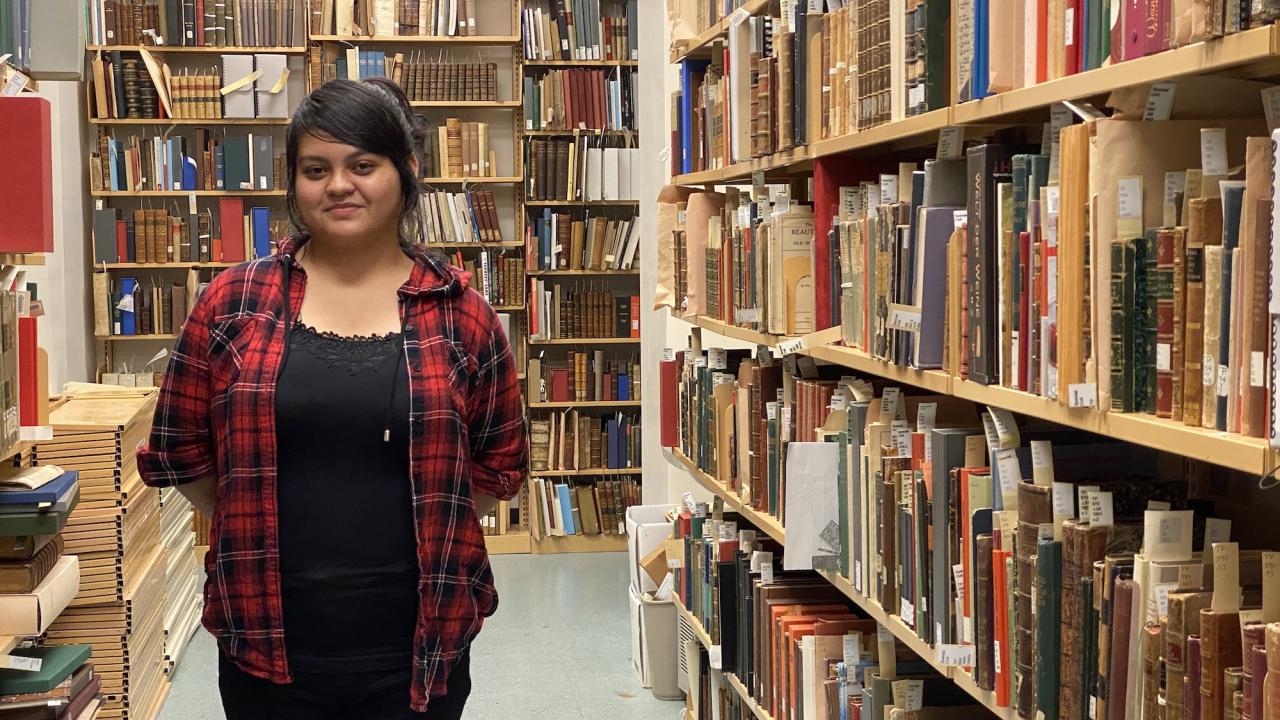 Student standing between library stacks at UC Davis. 