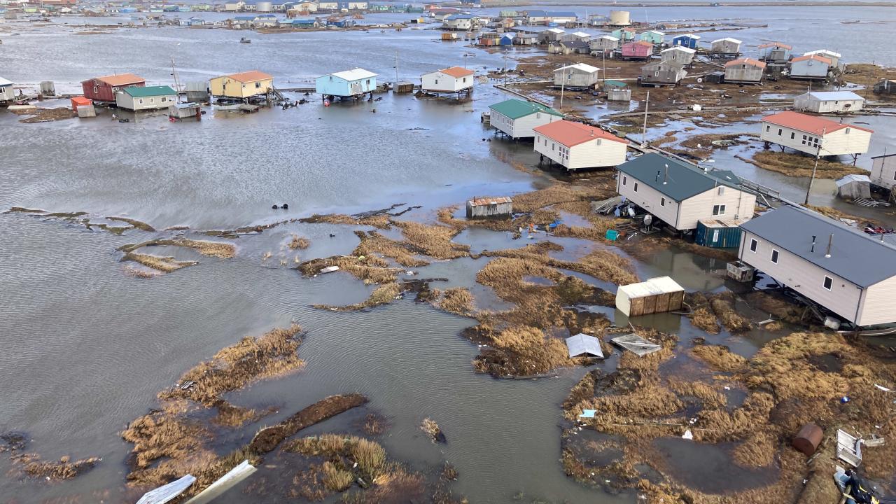 Aerial shot of typhoon-devastated Kipnik, Alaska, showing homes on stilts and rising waters