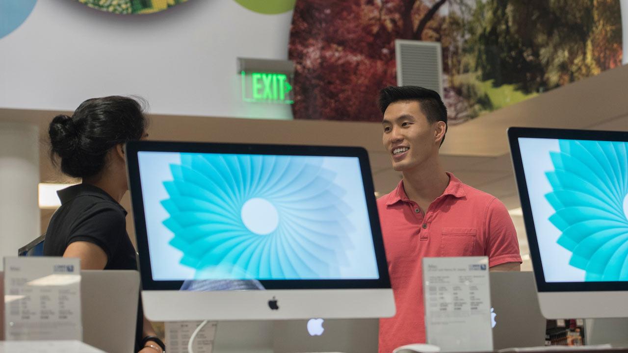 A UC Davis stores student staff member discusses computer options in the computer section of the flagship UC Davis store.