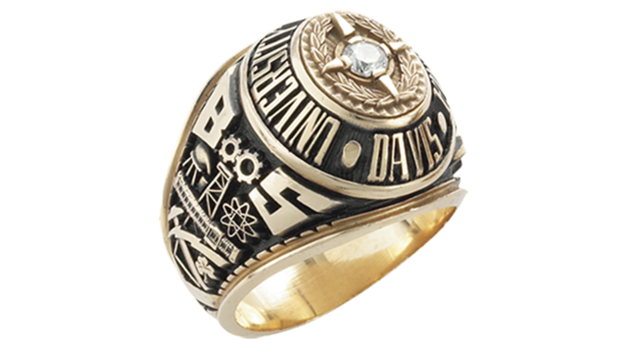 Gold and black class ring with central diamond, studio photo