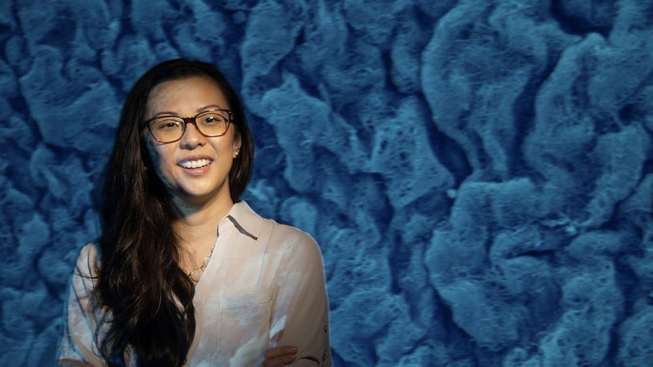 A student stands in front of a cell structure image