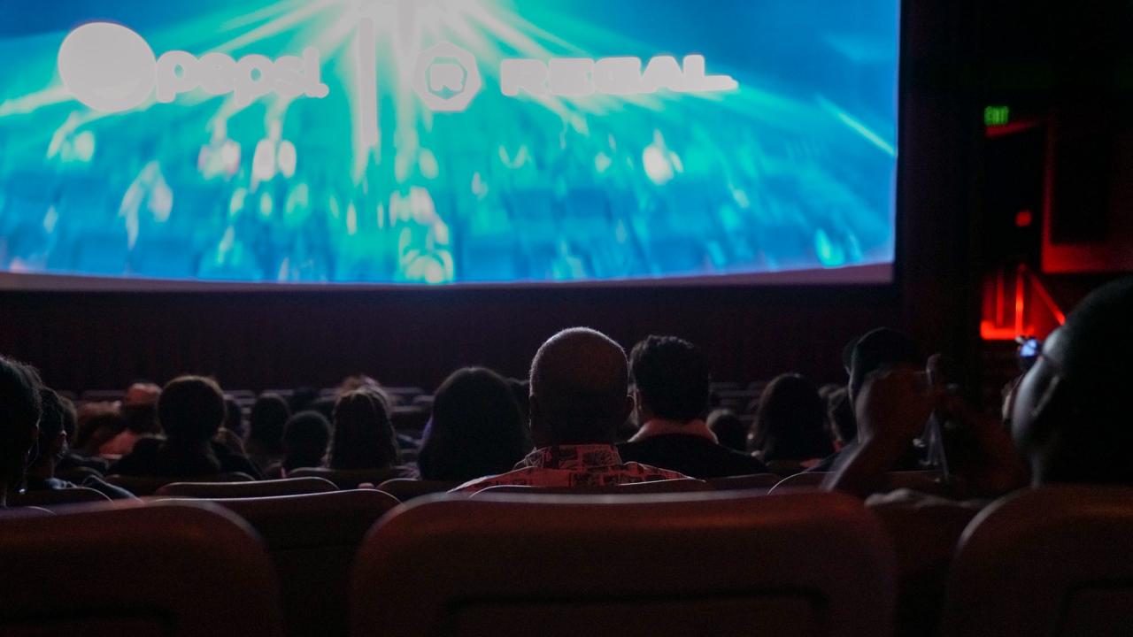 Chancellor Gary S. May, back to camera, watches movie in theater