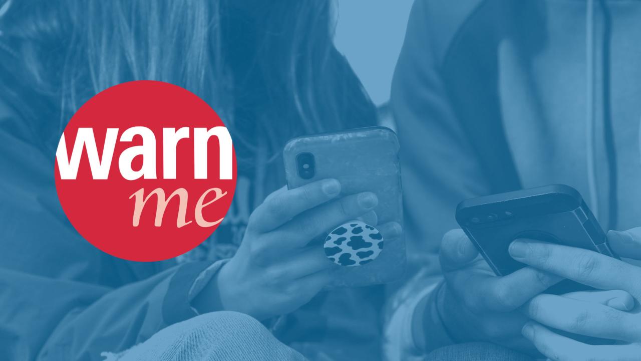 Red WarnMe logo against a blue background of a cell phone in hands