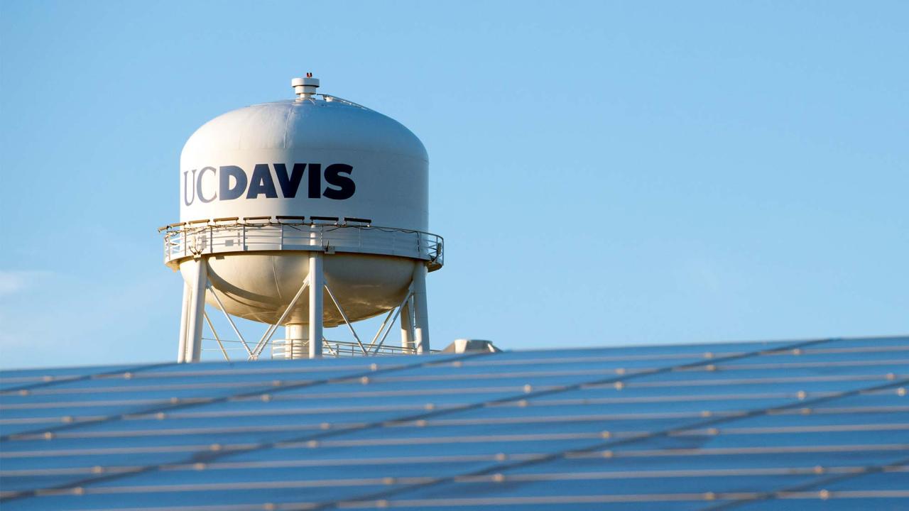 Campus water tower seen with solar panels in the foreground.