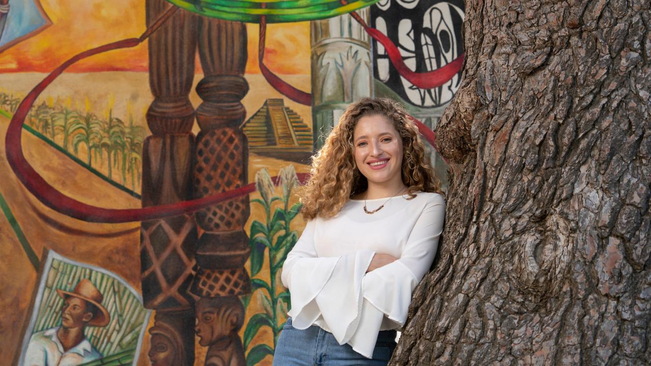 A student poses beside a mural. 