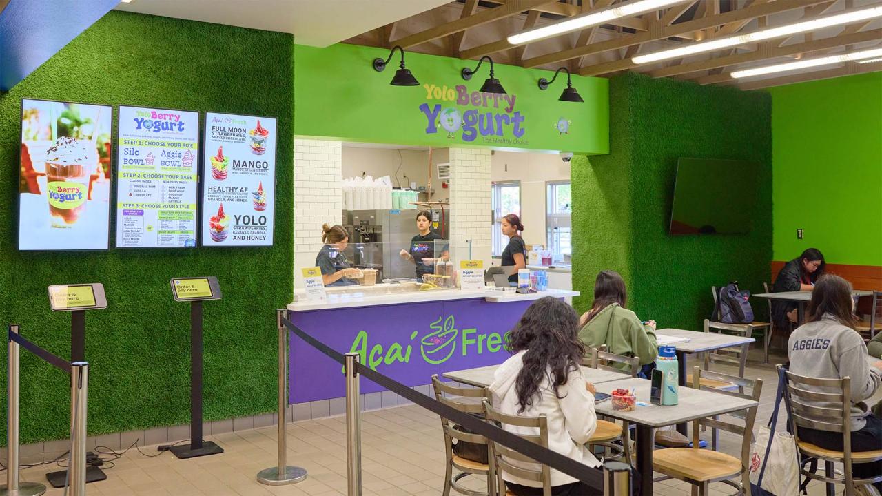 Green-accented acai café interior with service counter, digital menus and seated customers