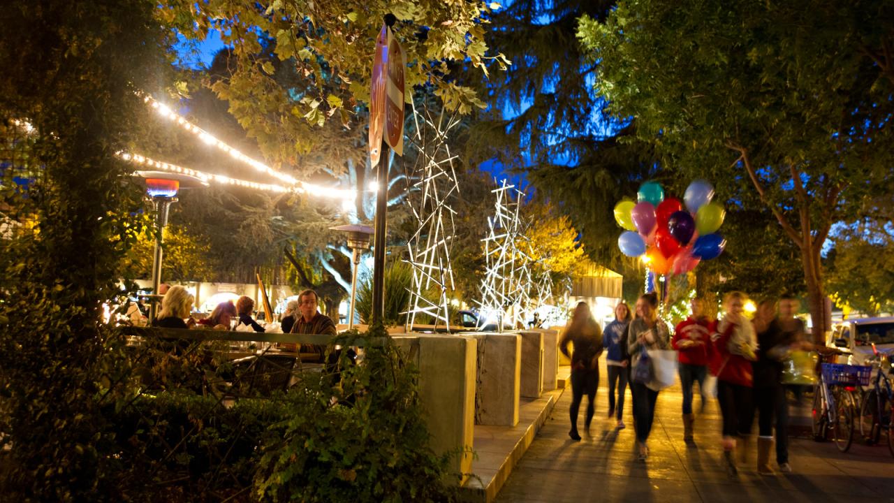 People walking in downtown Davis in the evning with balloons