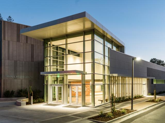Building exterior in the evening, with lights shining from inside glass-walled lobby 