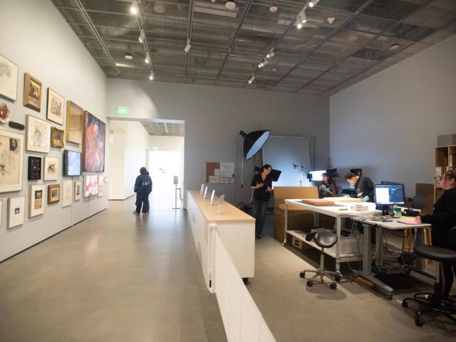 A spacious gallery with framed artwork on the walls; a reception area in the foreground.
