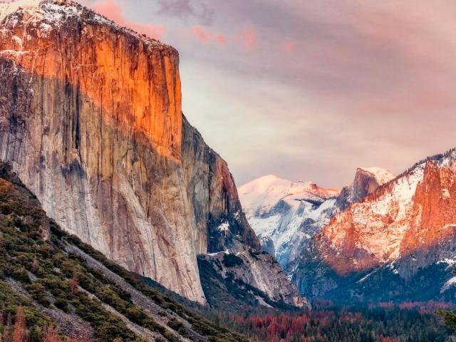 A beautiful landscape view of Yosemite valley with its rising cliffs and falling waterfalls all wrapped in a warm sunset.