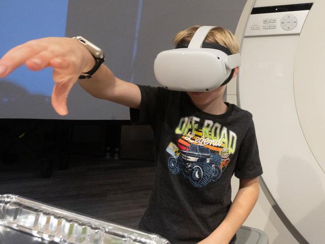 Child with a virtual reality headset on tries to solve a puzzle