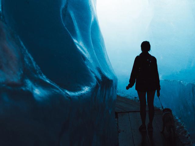 A silouette of a person walking into a glacier with her dog