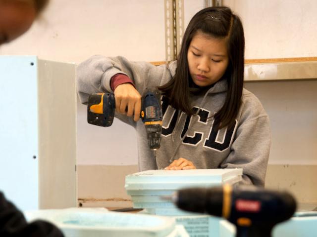 A female student uses a power drill at the craft center