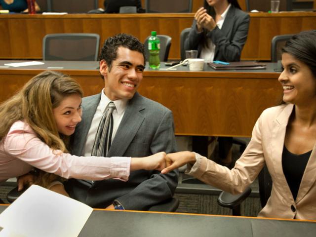 students fist bump after a win at the law school