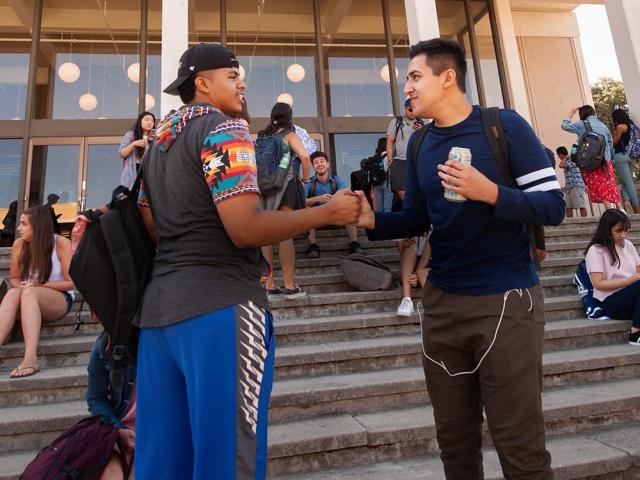 two students chatting on steps in front of building - transfer application tips